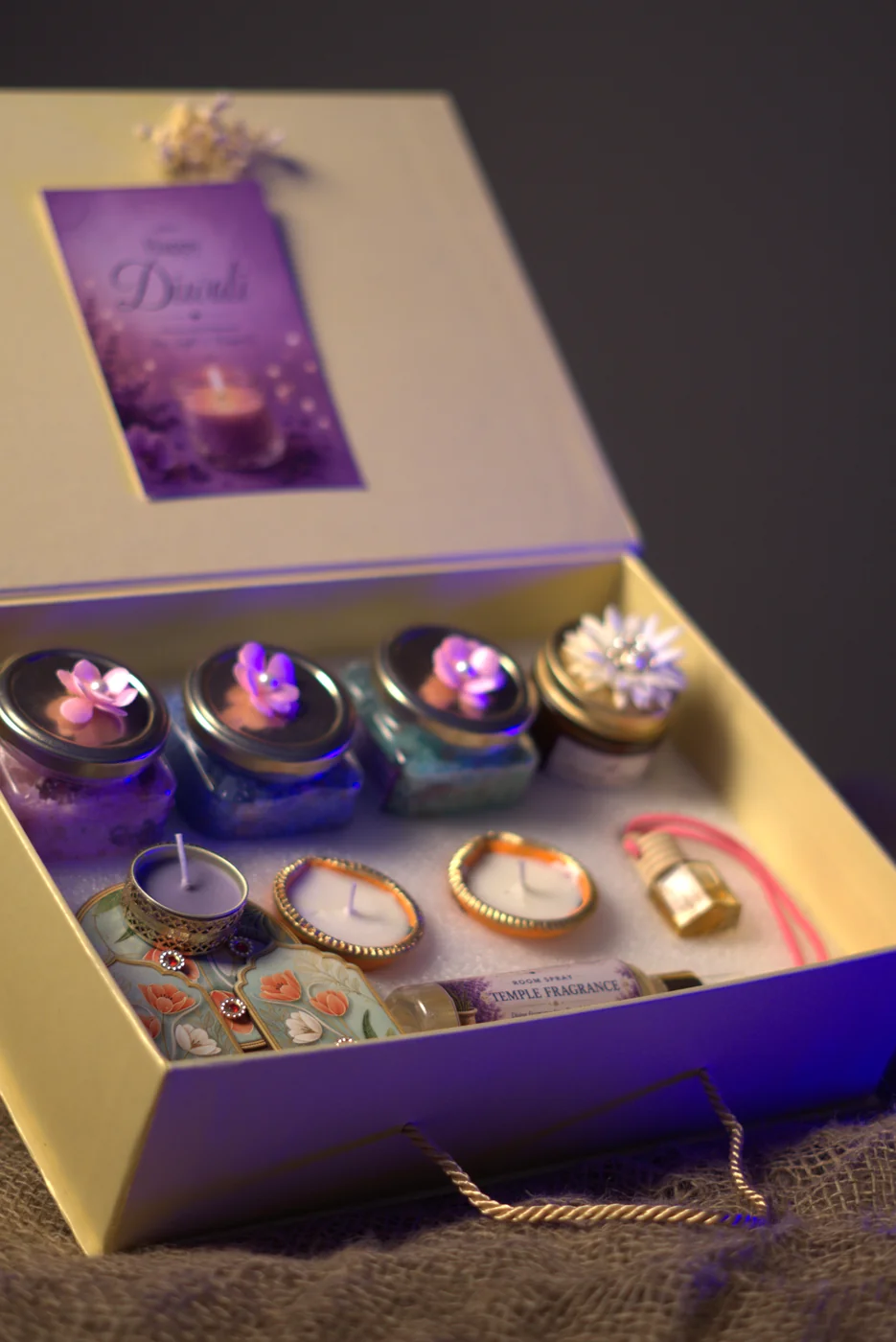 Open Diwali gift box with bath salt jars, diyas and a candle