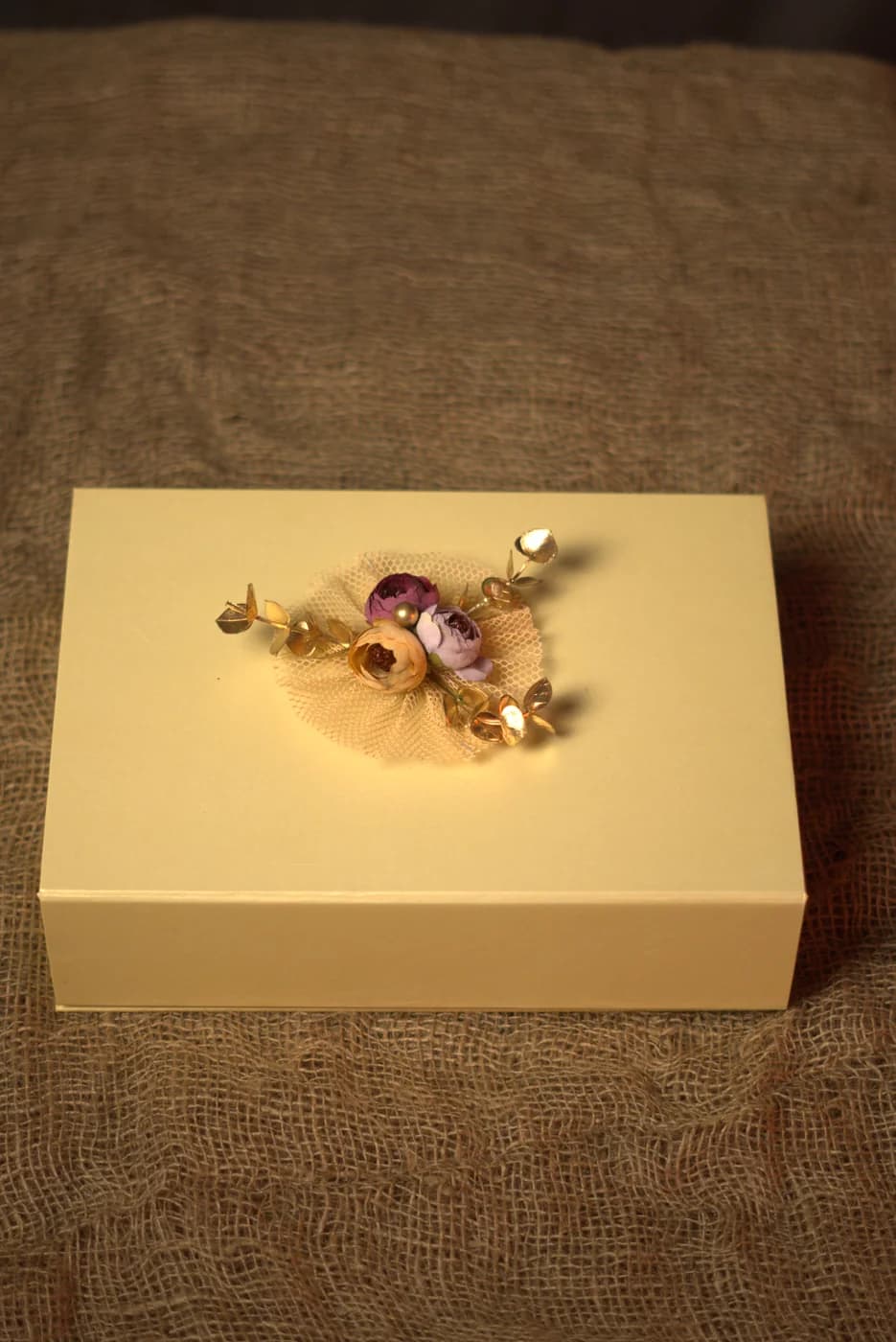 Cream hamper box finished with a gold floral brooch